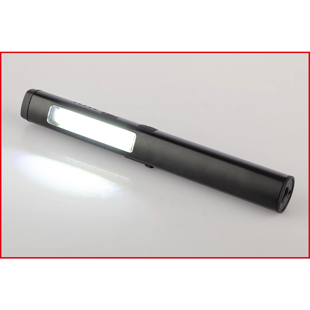 Zwarte LED-werklamp, ingeschakeld. Het lichtgevende oppervlak is rechthoekig, het licht wordt naar beneden uitgestraald. Aan/uit-knop.